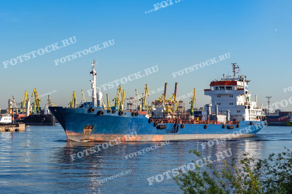 Фотография грузового судна, пришвартованного в порту на фоне множества кранов. Сцена демонстрирует активную логистическую деятельность и инфраструктуру порта.